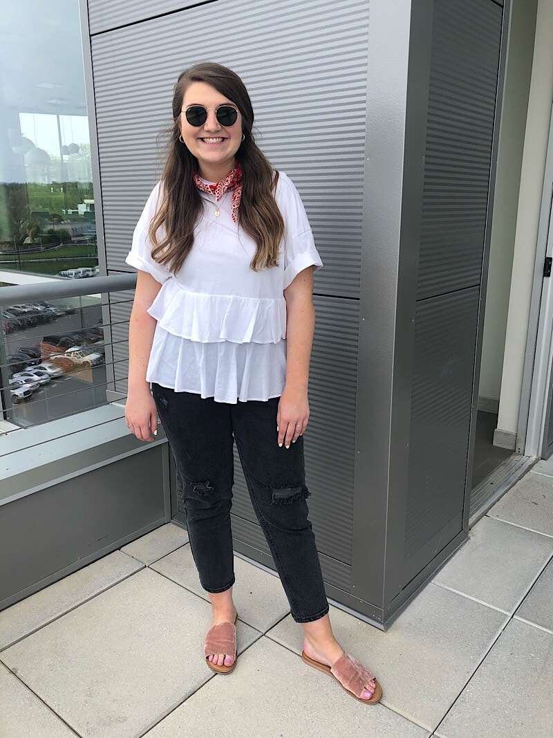 Ali, a student at West Virginia University, wears a layered ruffle white shirt with short sleeves, a red bandana ascot, round sunglasses, black cropped jeans, and flat blush velvet slide sandals.