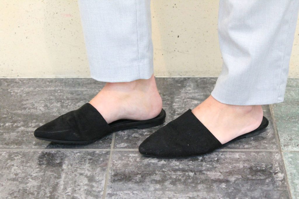 Darby wears flat black pointed-toe slide shoes.