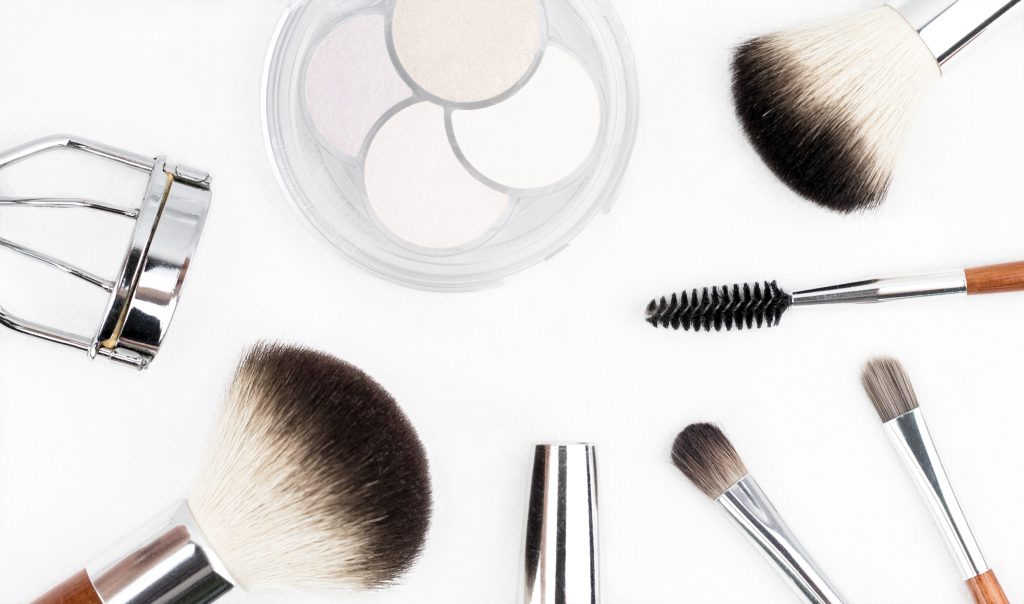 Makeup quiz - what makeup brand are you? Photo of makeup brushes and eyelash curler laid out on a table