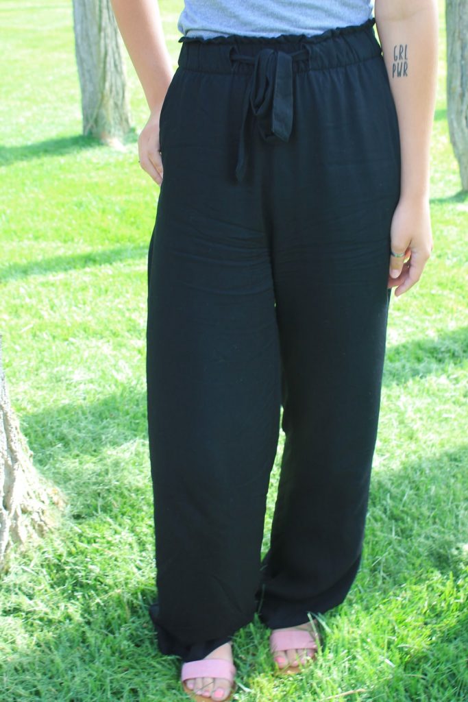 Emily wears flowy loose-fitted black pants with a tie at the waist.