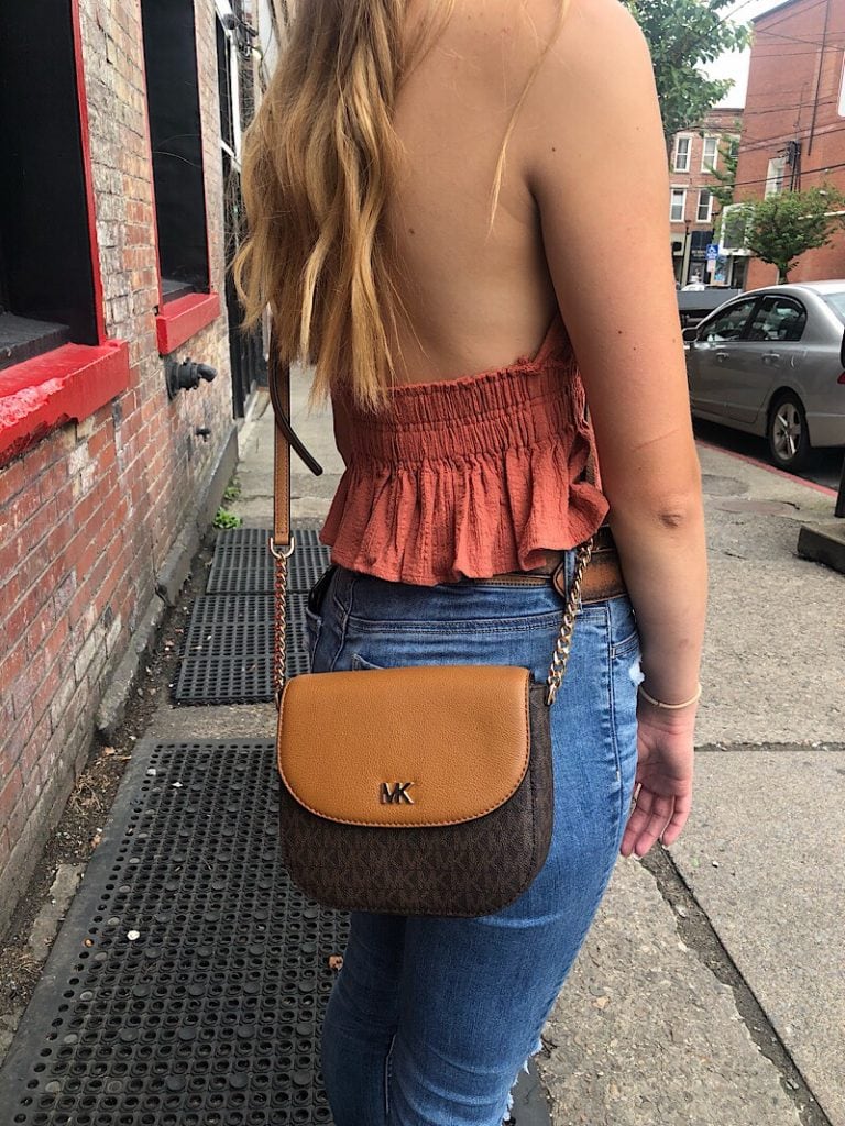 This West Virginia University student wears a tan and dark brown Michael Kors crossbody bag.