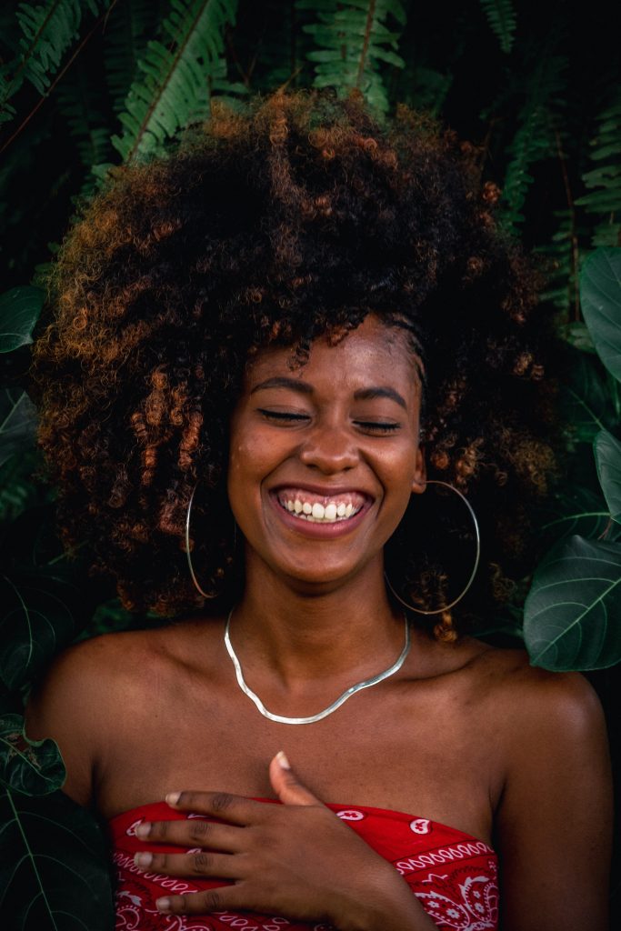 Close-up shot of woman with afro-texture hair standing amongst leaves