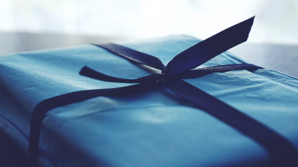 Close-up photo of blue wrapped gift with navy blue ribbon