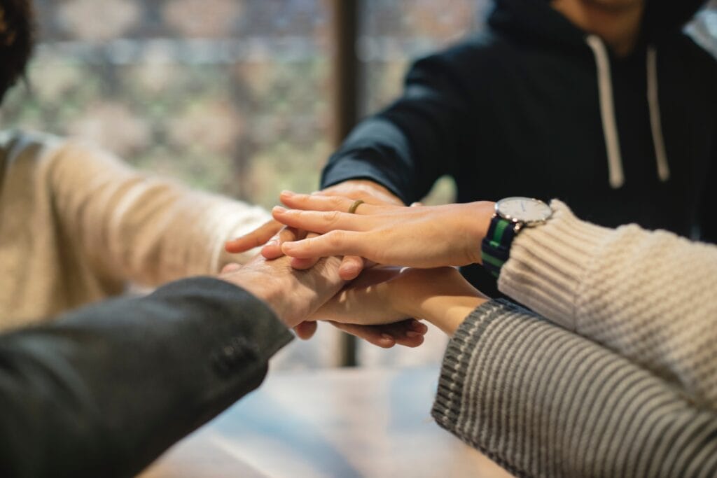 A team stands in a circle, their hands stacked in the center of the circle.