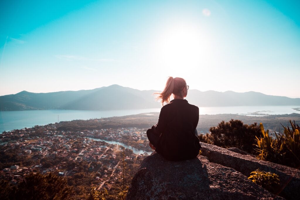 Tips for introverts in college - Woman sitting alone in nature, looking at the mountains.