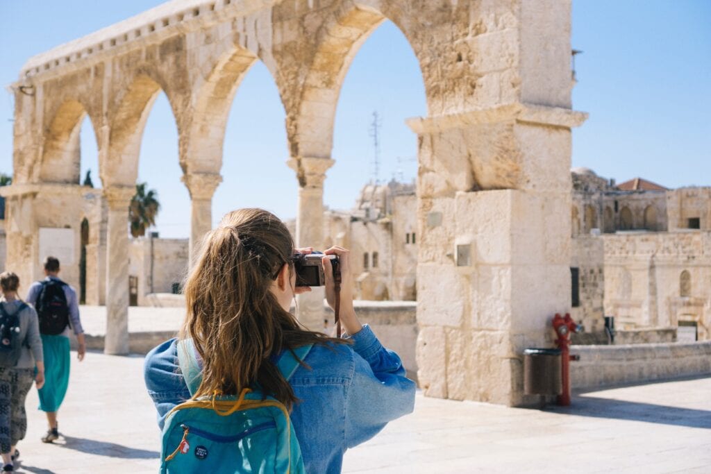 How to travel in college: Study abroad. Student taking photos of historic building.