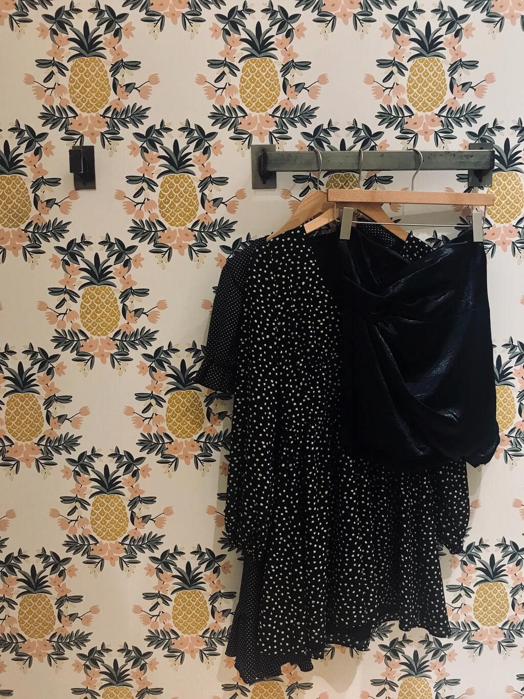 dresses and skirt hanging in front of pineapple wallpaper