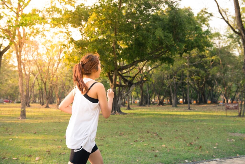 A young woman runs through a park.