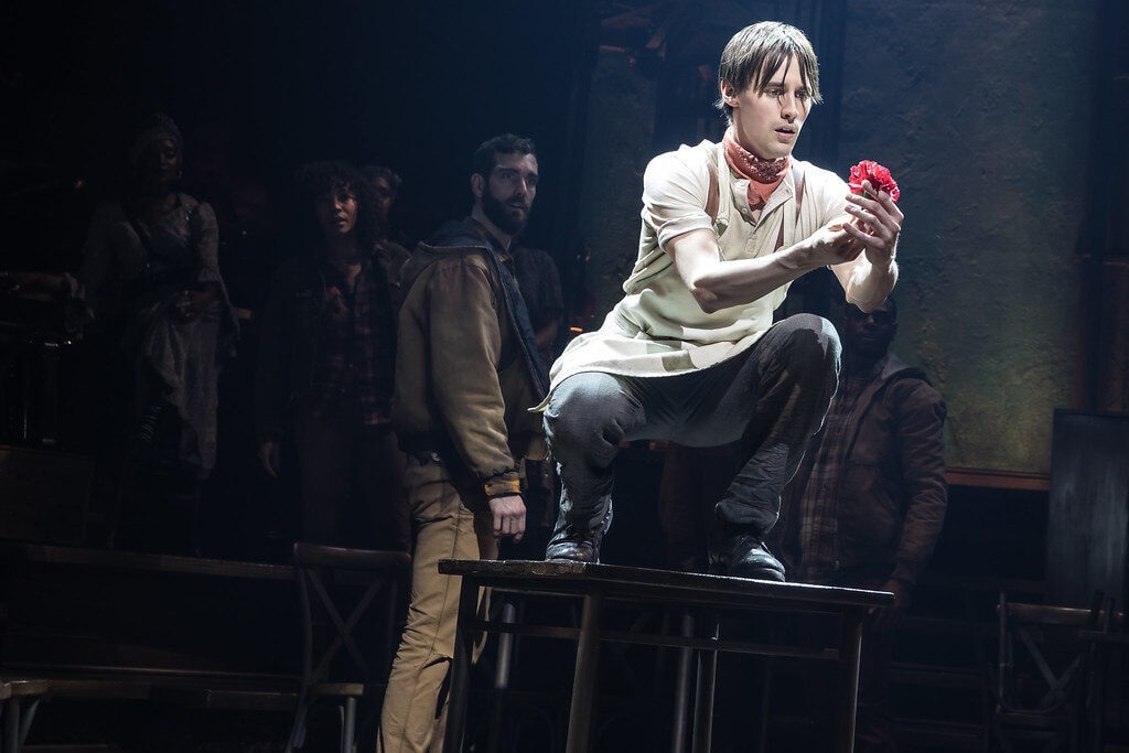 Promotional photo of Orpheus holding a flower - hadestown costumes and hadestown fashion guide