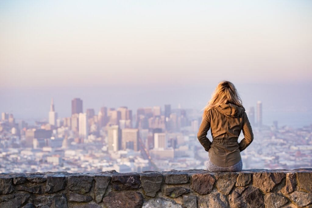 Young woman sitting, looking at city skyline.