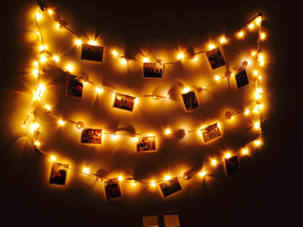 Photos + fairy lights on a dorm wall.