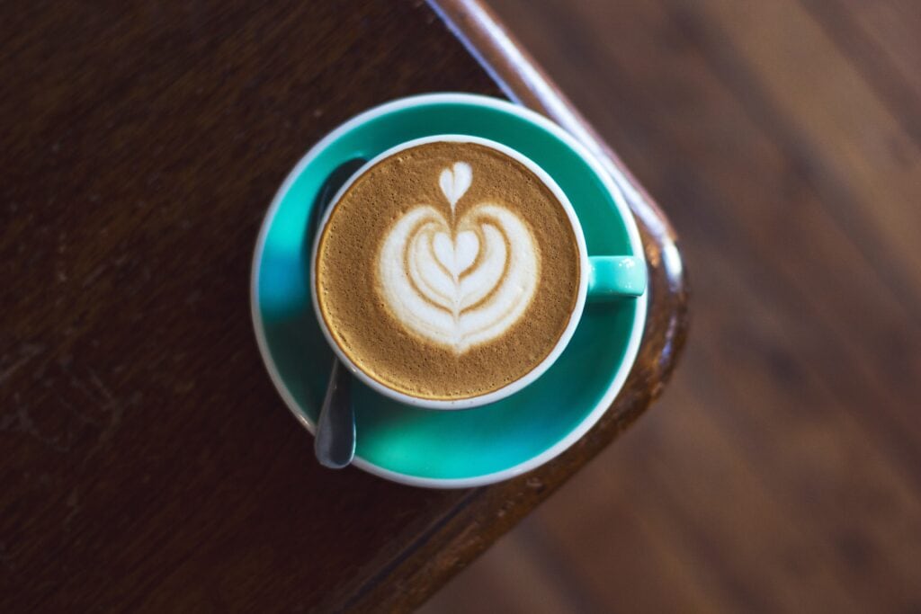 latte art in a teal mug with a teal plate and spoon