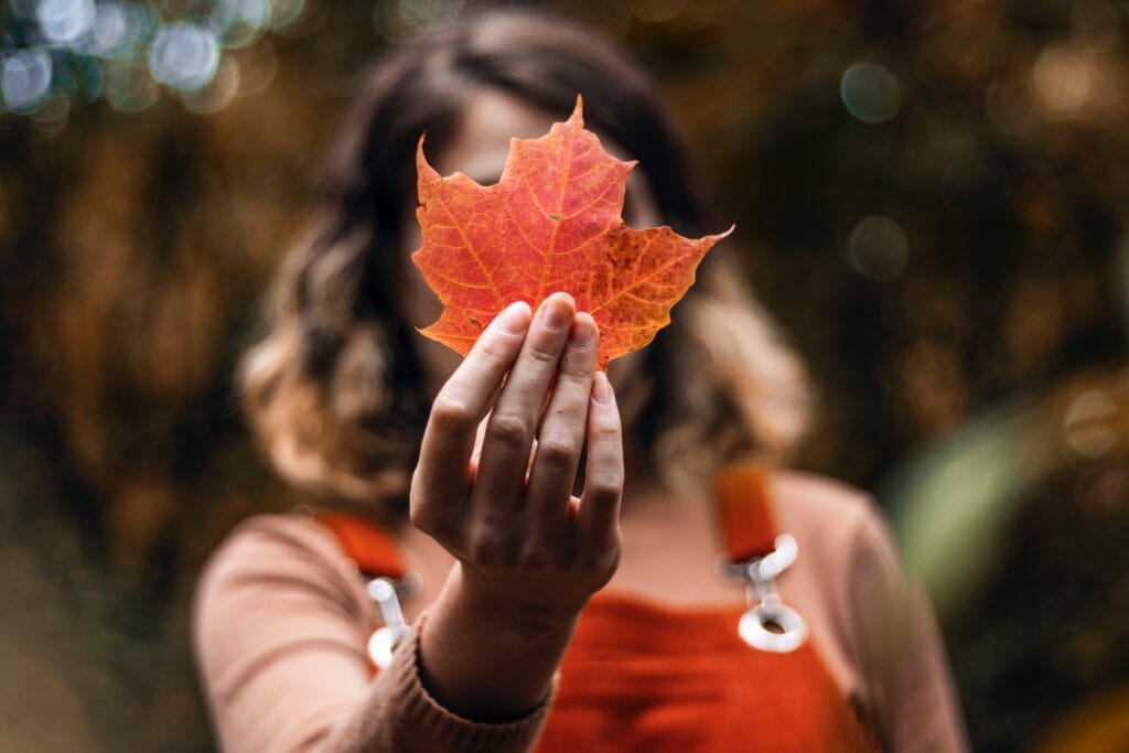 Girl holding autumn leaf.