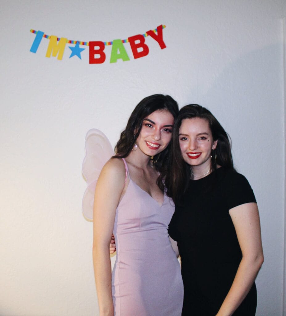 Photo of two girls (author pictured) under a wall decoration