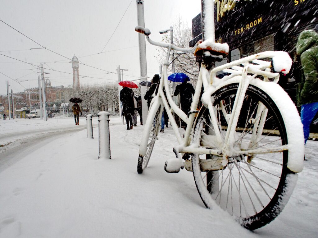 Bikes covered in snow in city.