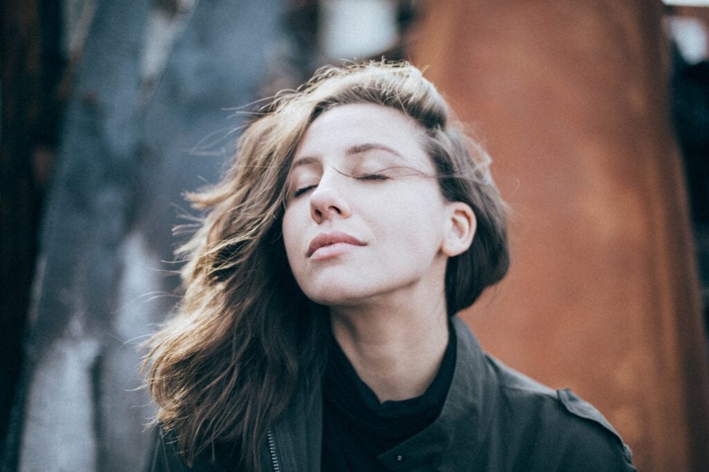 Woman with eyes closed and wind blowing her hair