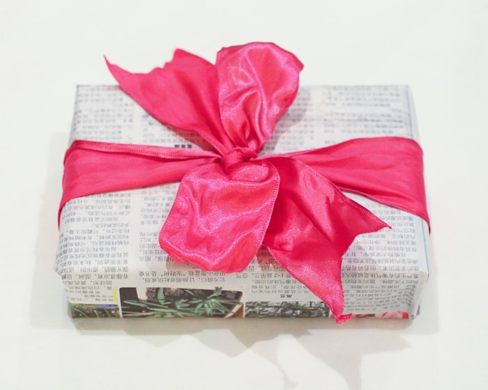 Gift wrapping ideas - newspaper wrapped present with pink bow.