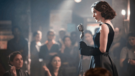 Mrs Maisel fashion: Photo of Midge Maisel from The Marvelous Mrs Maisel wearing a black dress and gloves while performing