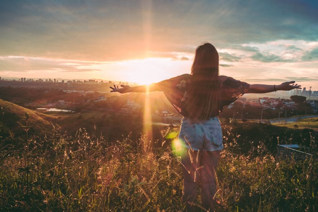 Girl standing on mountain looking towards the horizon.