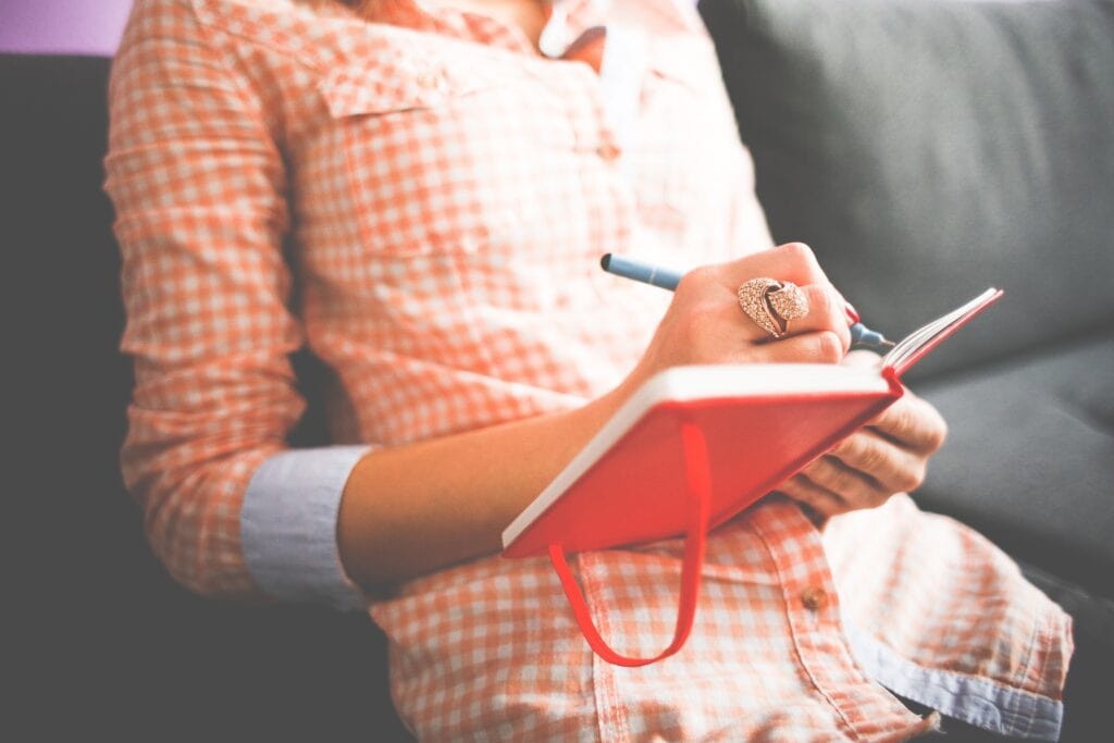 girl writing in red journal