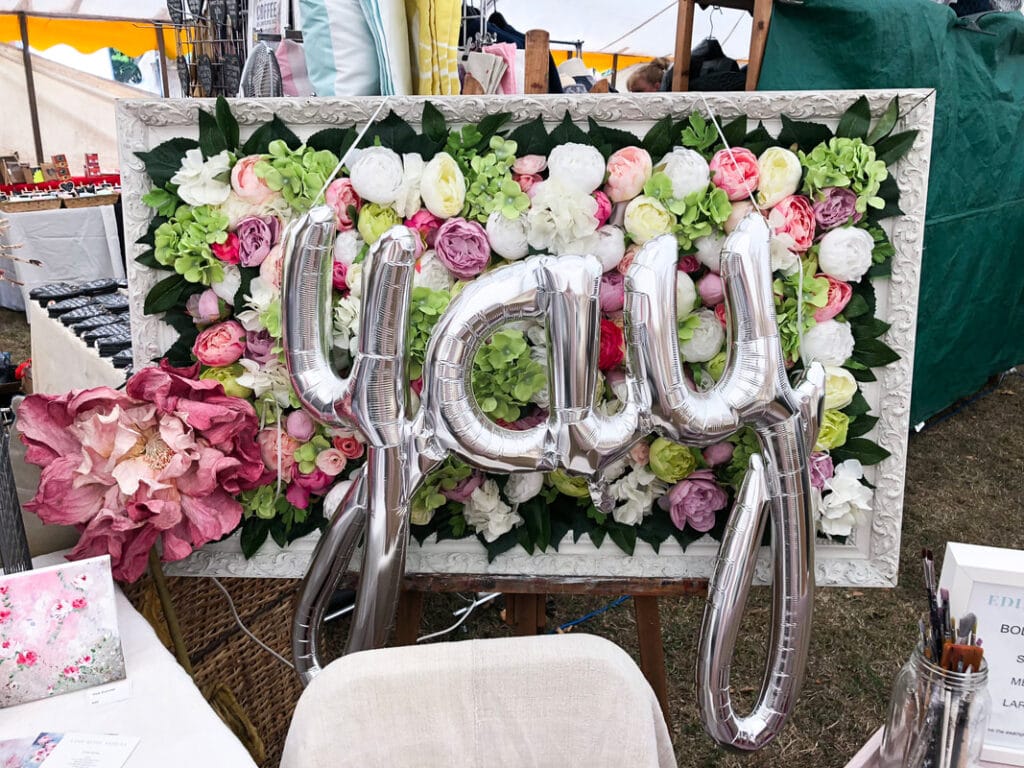 Spring DIYs: frame full of flowers behind yay metallic balloons