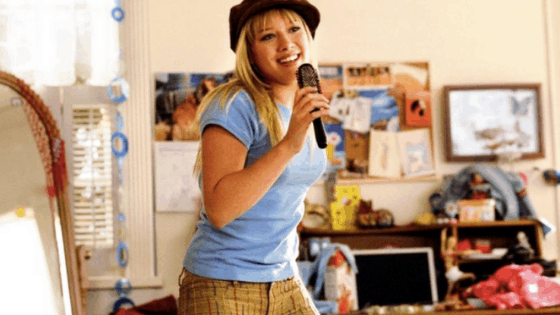 Still from the Lizzie McGuire movie, singing into her hairbrush.