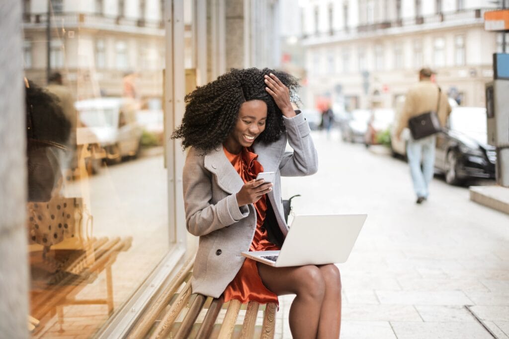 woman in gray coat laughing on bench