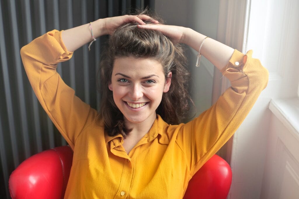 Woman in yellow shirt styling hair.