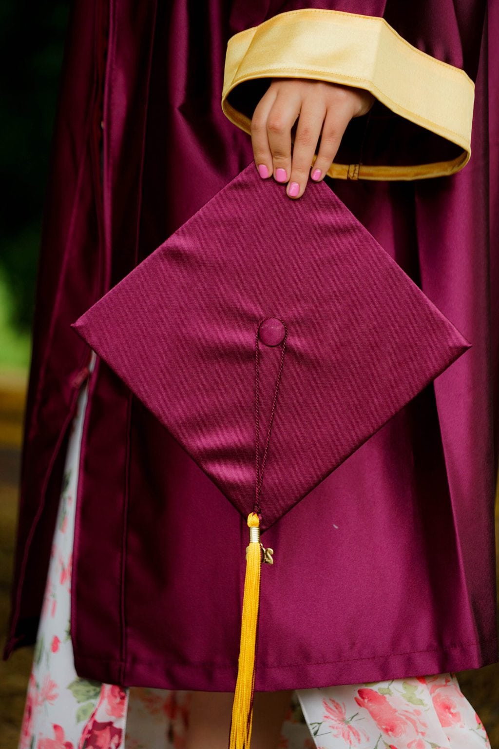 Graduation image of a woman in a graduation gown holding her cap.