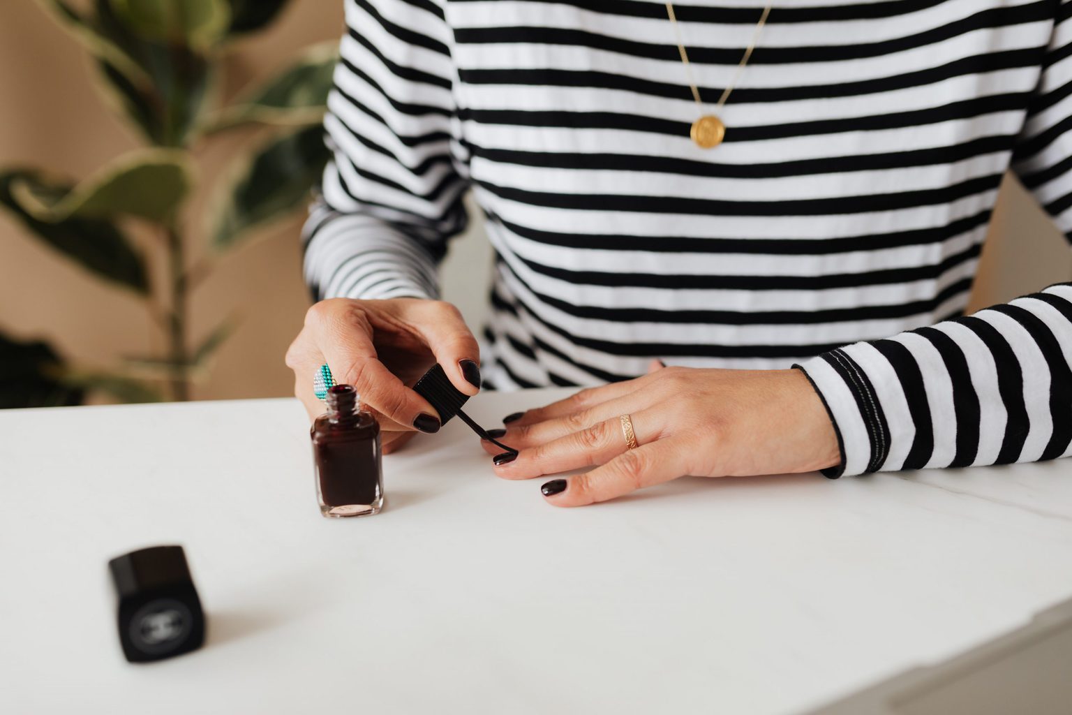 woman in striped shirt puts on black nail polish for an at home manicure from Karolina Grabowska at Pexels