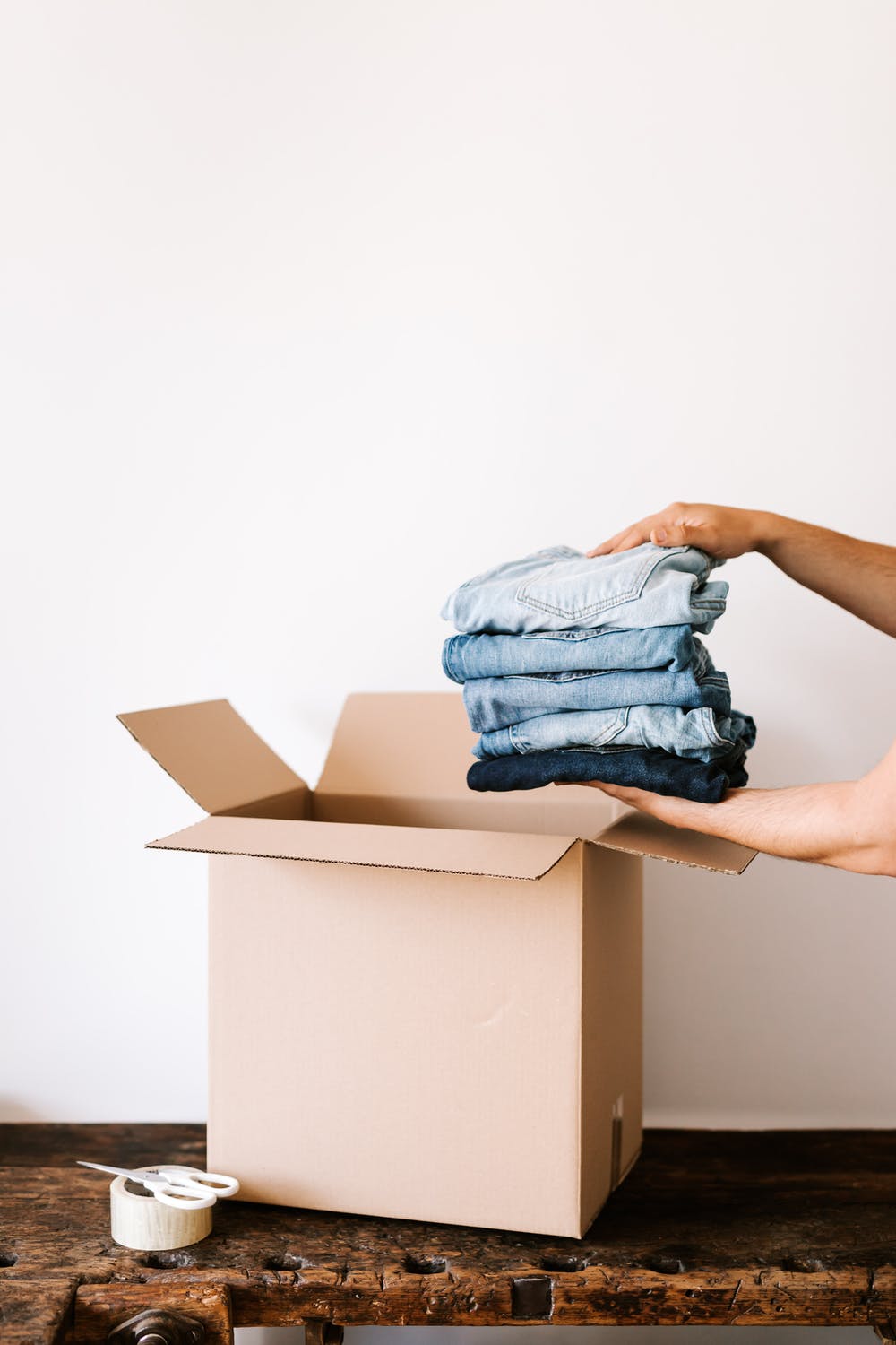 person putting jeans into a cardboard box