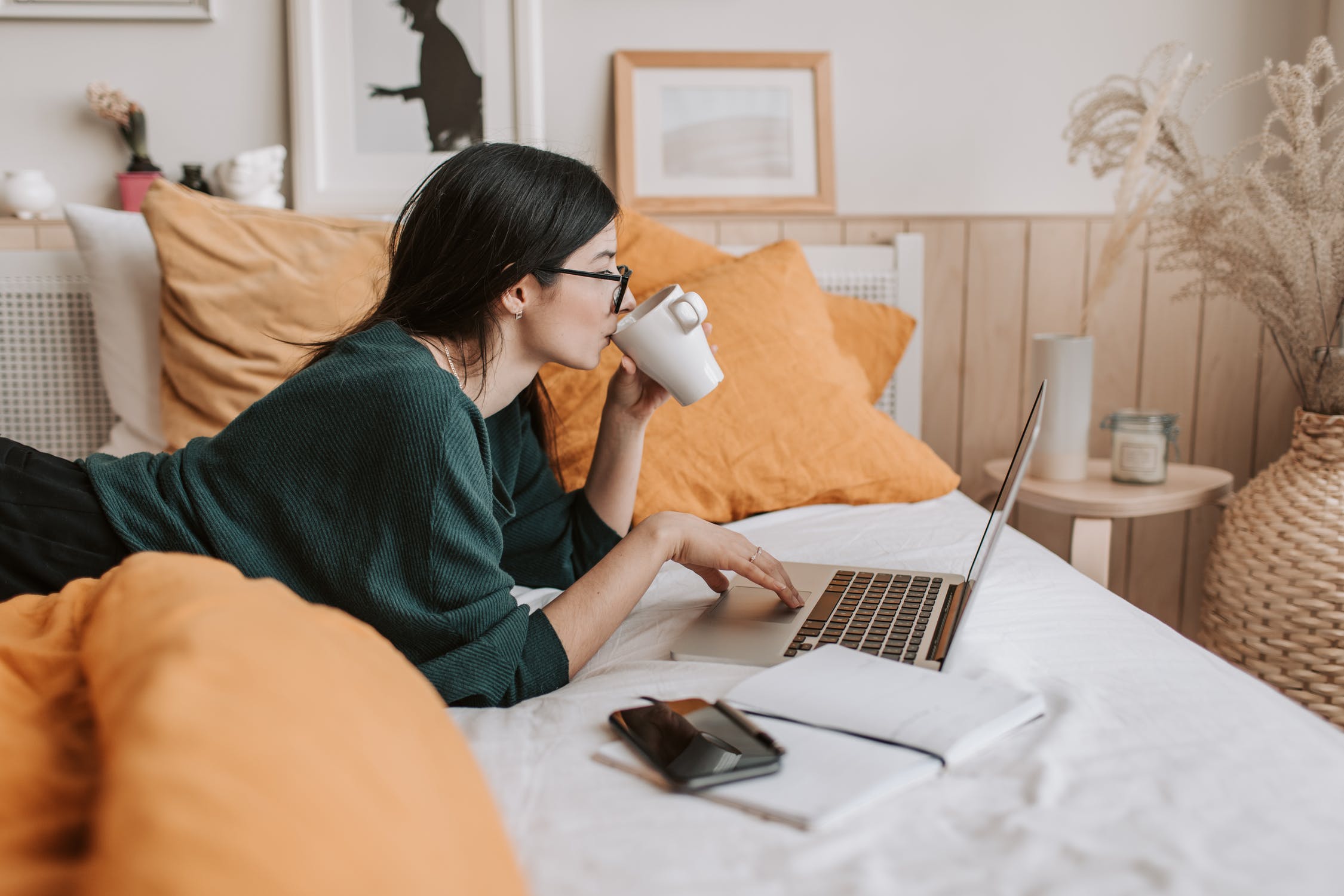 Girl sipping coffee while working on her laptop in bed. how to find your style.