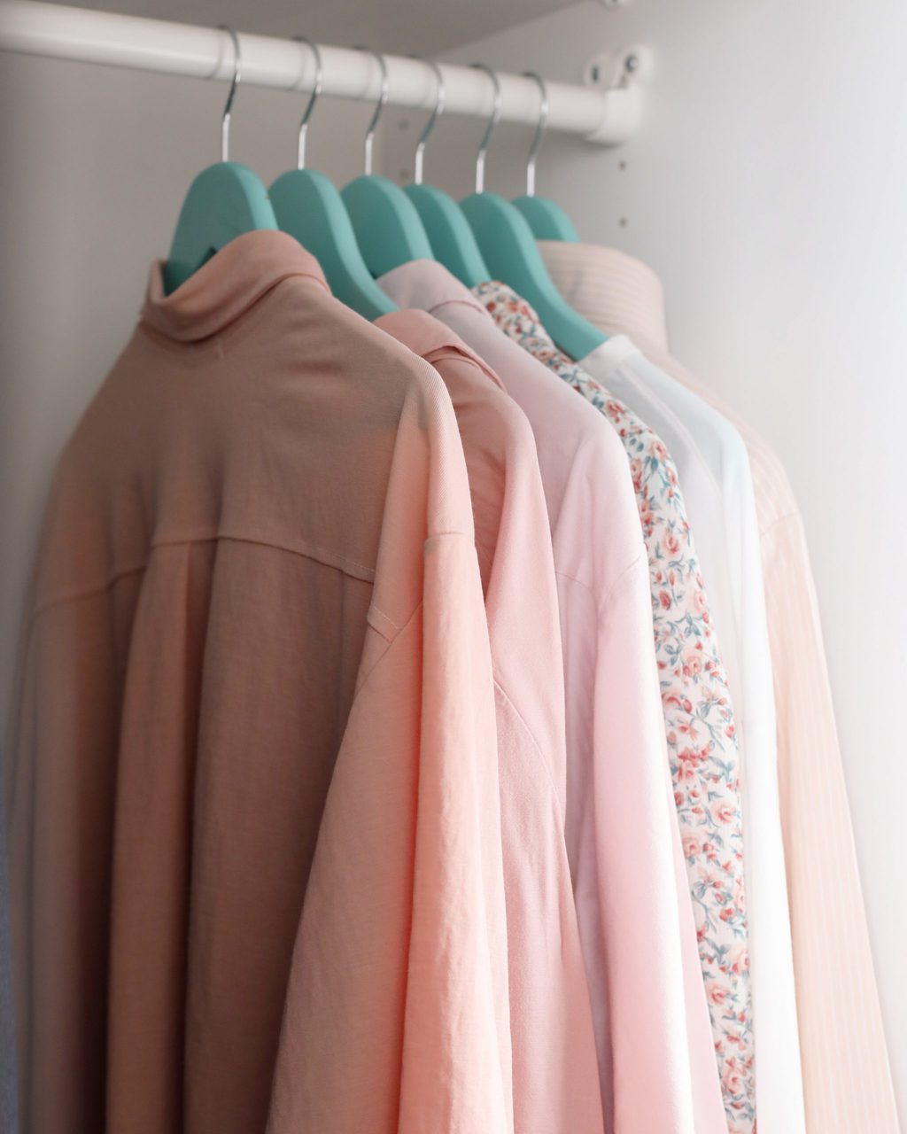 rack of clothing with light pink and salmon colors blouse with flowers
