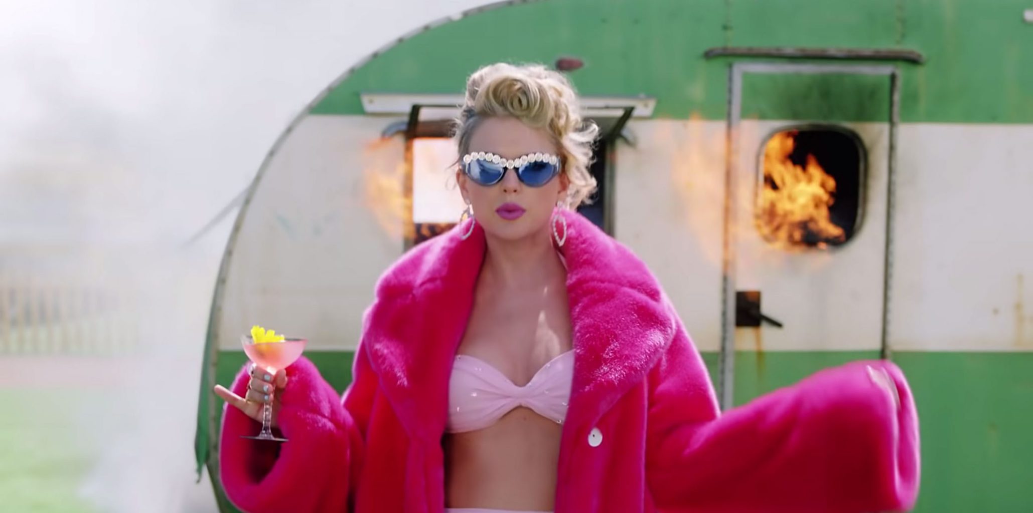 Taylor Swift in a bright pink fur jacket on the You Need To Calm Down music video set