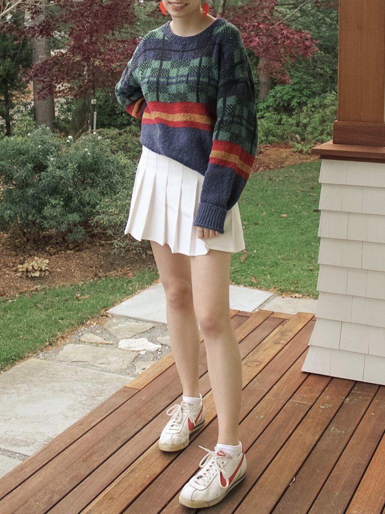 Photo of the author's outfit with a patterned sweater and a white tennis skirt