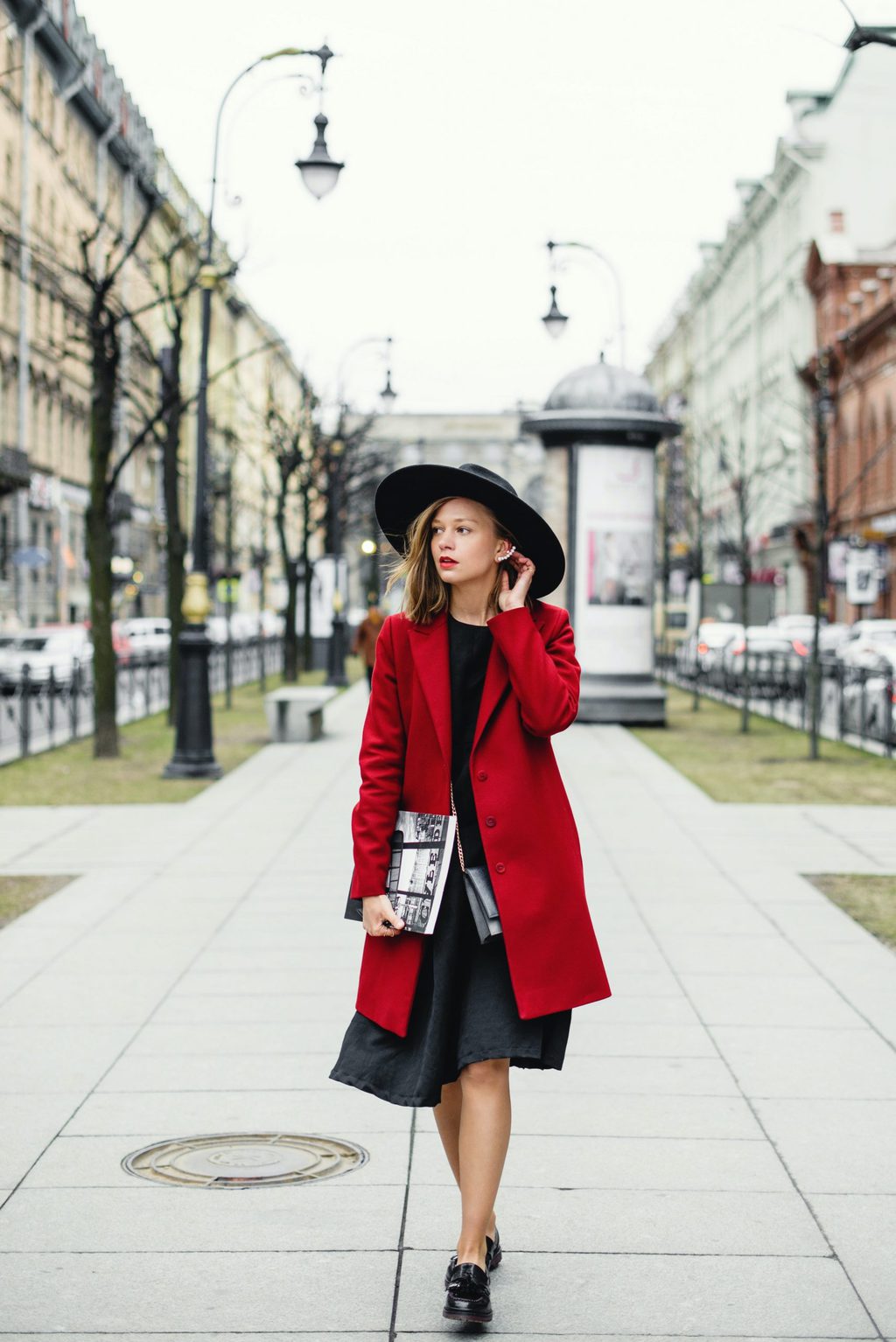 girl walking in all black outfit and red coat, holiday style tips