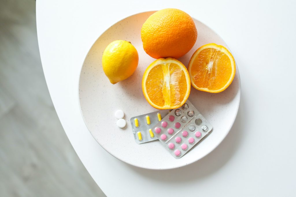 Best skin care habits - taking supplements. Stock photo of vitamins and oranges