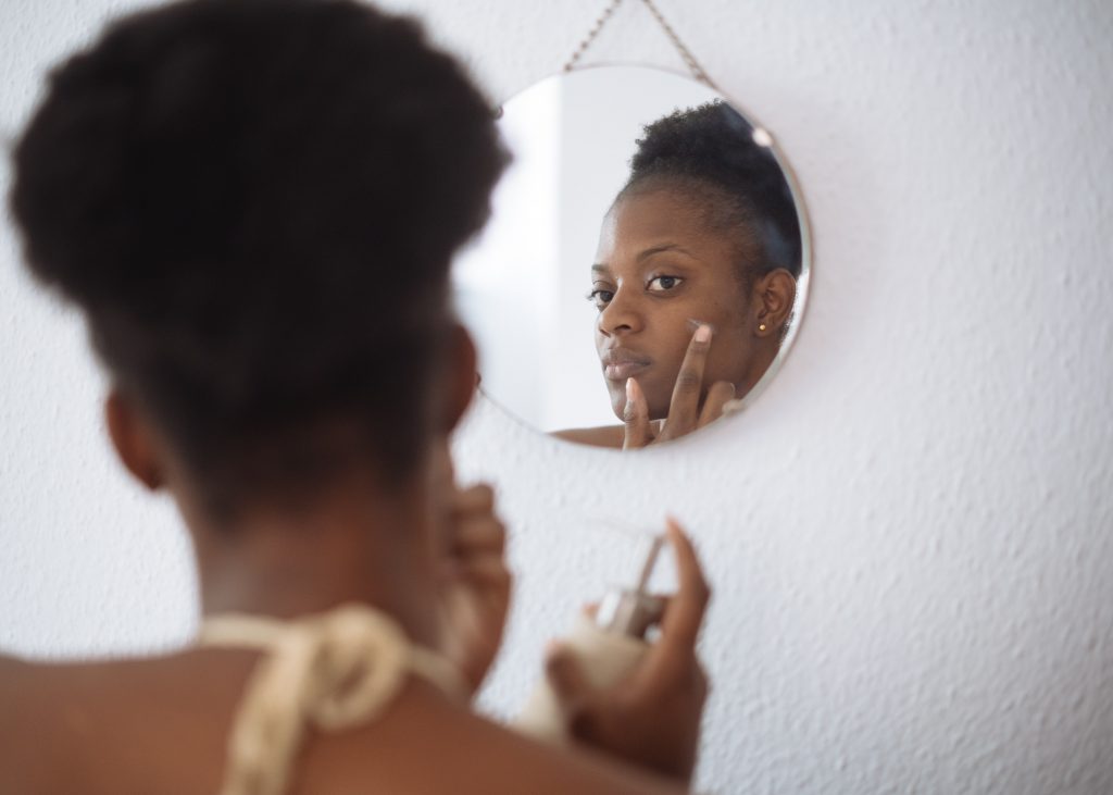 Best skin care habits - Stock photo of a woman rubbing a skincare product onto her face