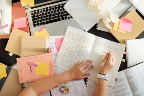 Messy desk with laptop, planners, notebooks, and journals, by Cottonbro from Pexels