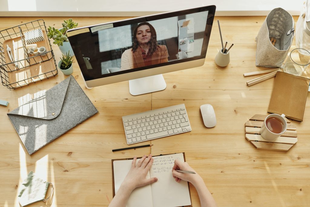 Makeup for Zoom: A girl taking notes at a desk during a video call. 