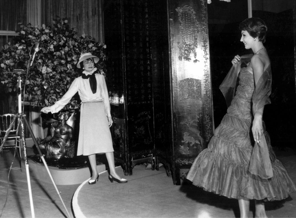 Coco Chanel admiring an evening dress