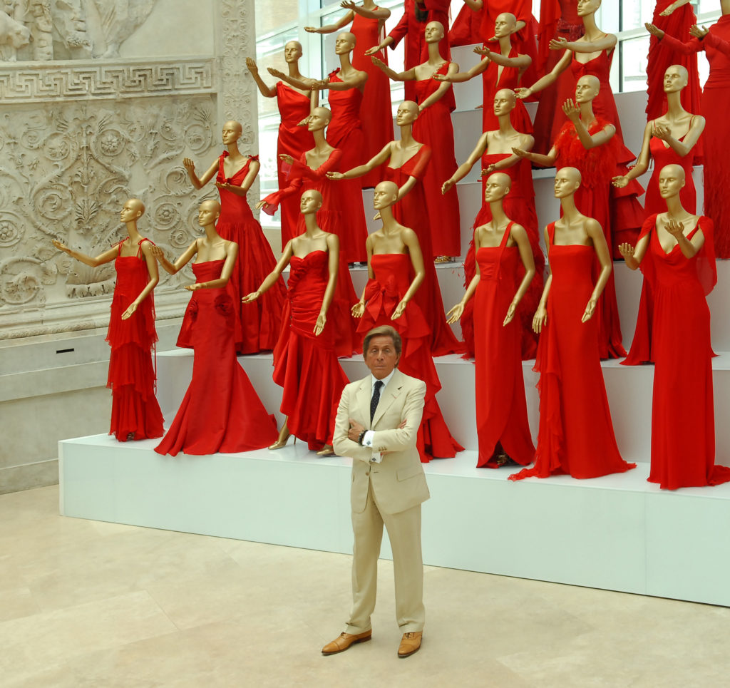 Valentino at an exhibit with his red dresses