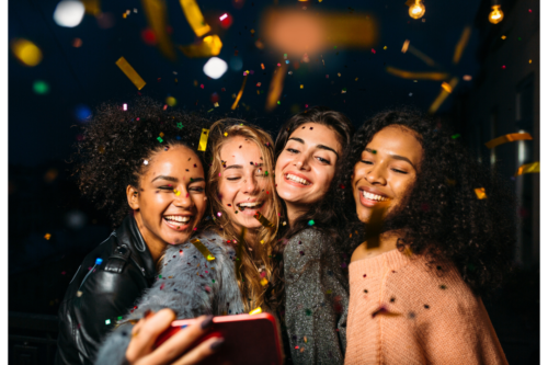 Photo of four girls celebrating a birthday while taking a selfie.