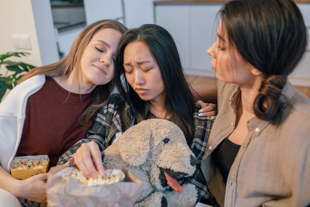 Three girls hugging with a dog toy. 