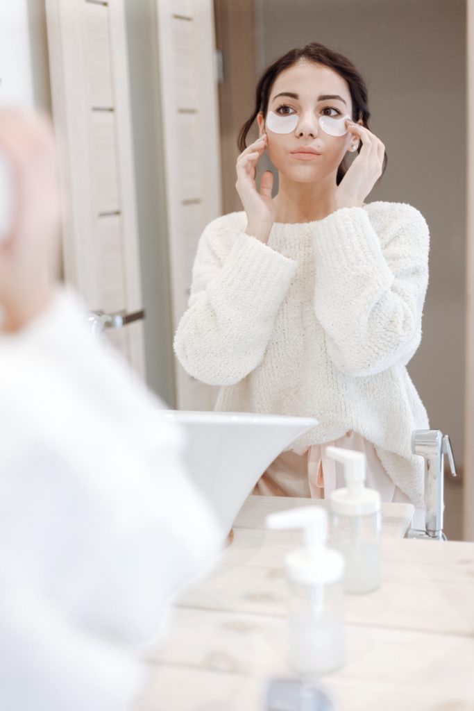 Woman with eye masks on looking in the mirror