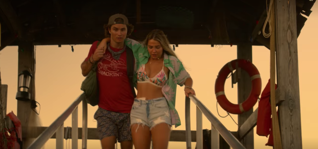 Outer Banks style Season 2: Photo of Sarah Cameron wearing denim cutoffs, a pink and green and white bikini, and a green and gray button-down shirt