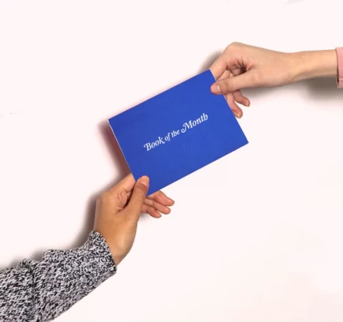 Two hands holding a Book of the Month subscription gift card.