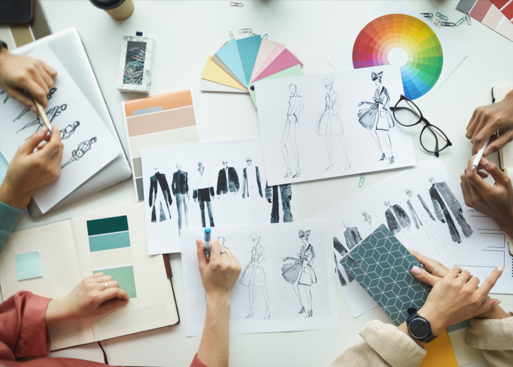 people gathered around a desk working on fashion sketches