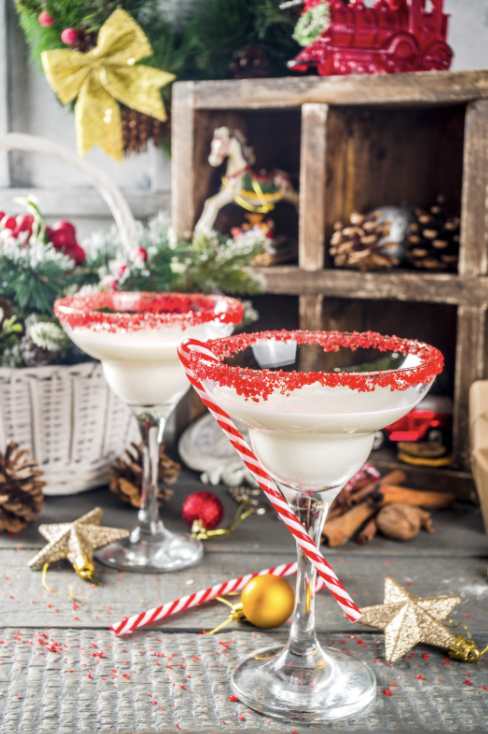 Two festive eggnog cocktails in martini glasses with red sugar rims and candy cane garnishes - christmas party ideas