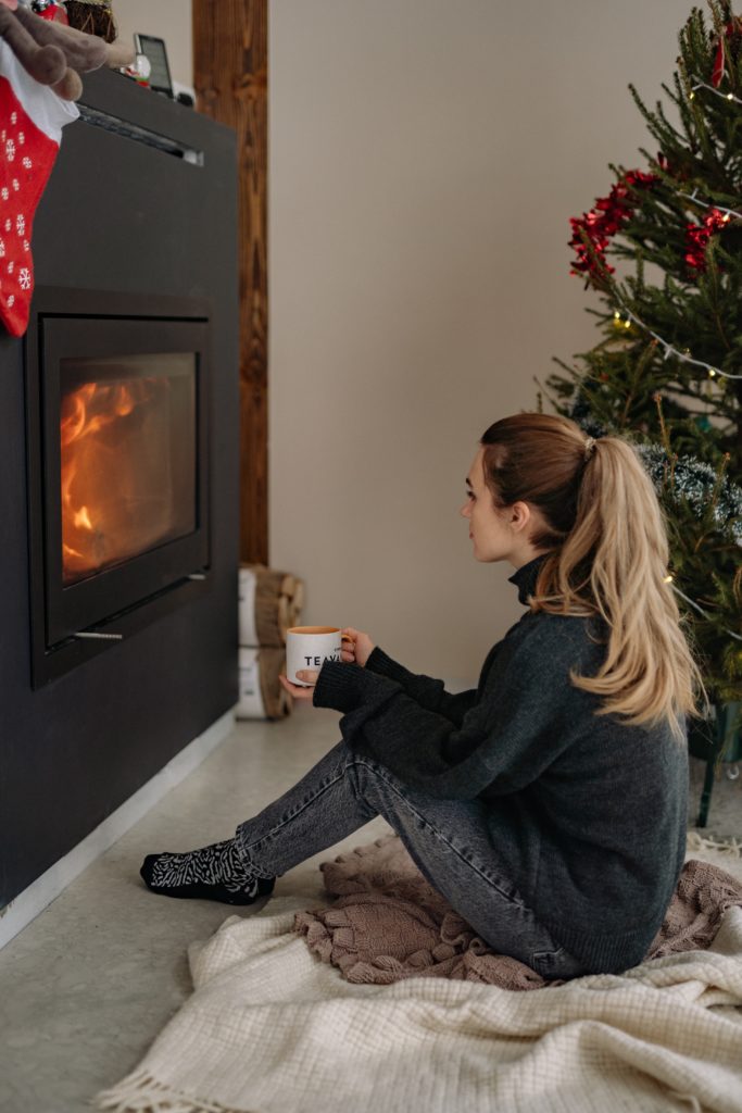 woman sitting in front of a fire drinking hot tea